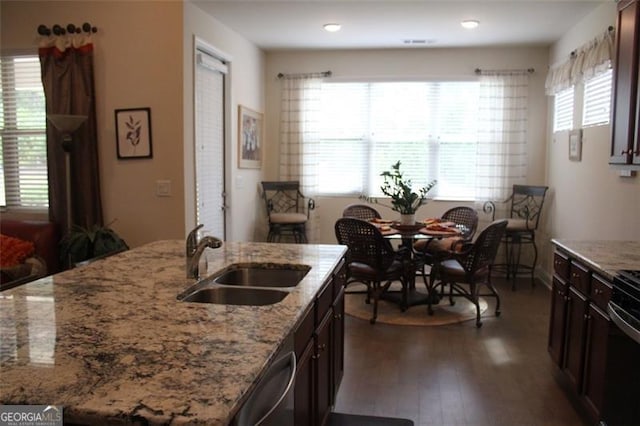 kitchen with light stone countertops, sink, dark wood-type flooring, dark brown cabinetry, and stainless steel dishwasher