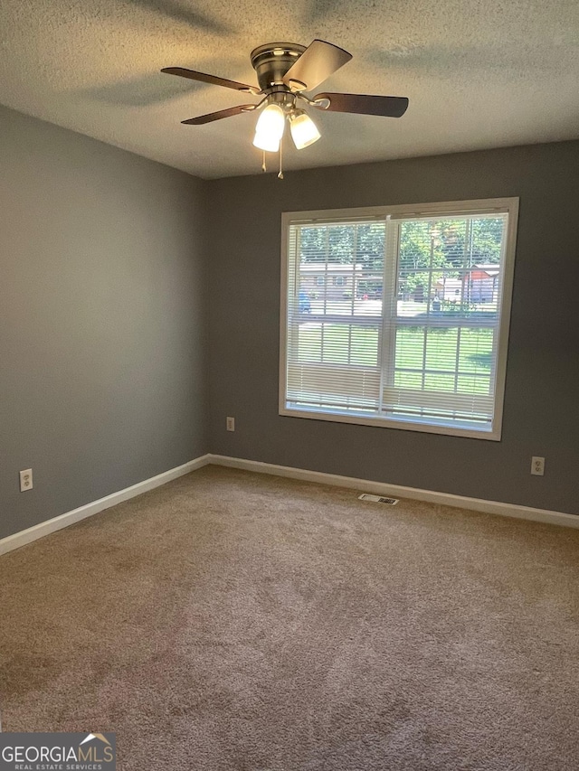 carpeted spare room with a textured ceiling and ceiling fan