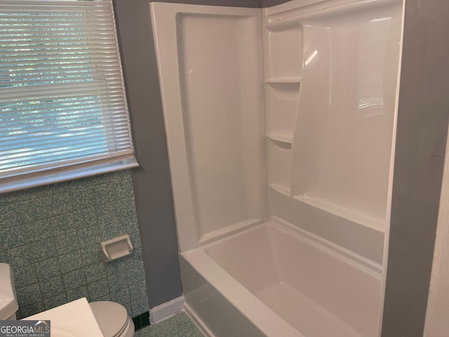 bathroom with a wealth of natural light, tile walls, and toilet