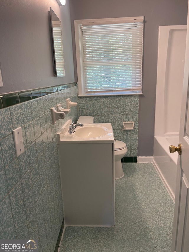 bathroom with vanity, toilet, and tile walls