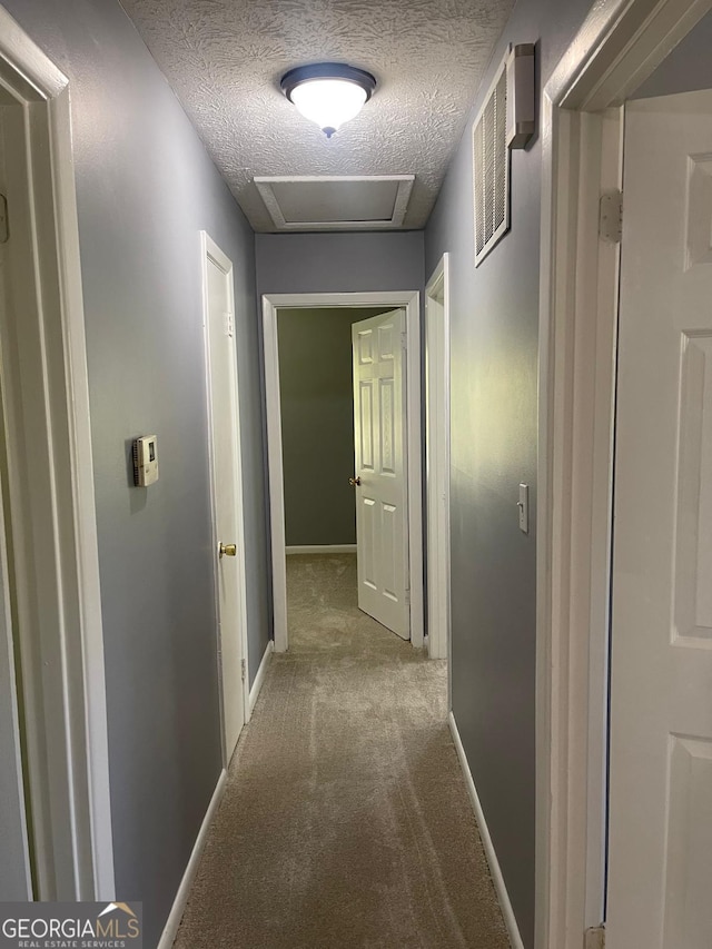 hall featuring carpet flooring and a textured ceiling