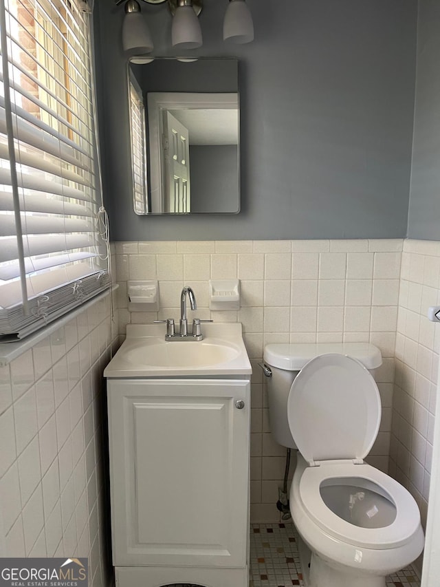 bathroom with tile patterned flooring, vanity, toilet, and tile walls