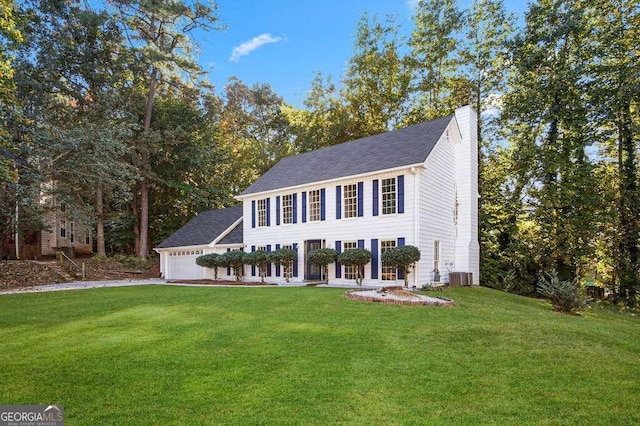 view of front of house featuring a front lawn, a garage, and central AC unit