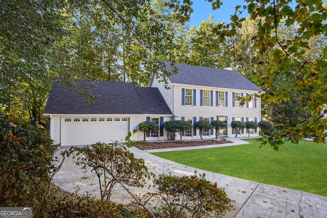 colonial inspired home featuring a garage and a front yard