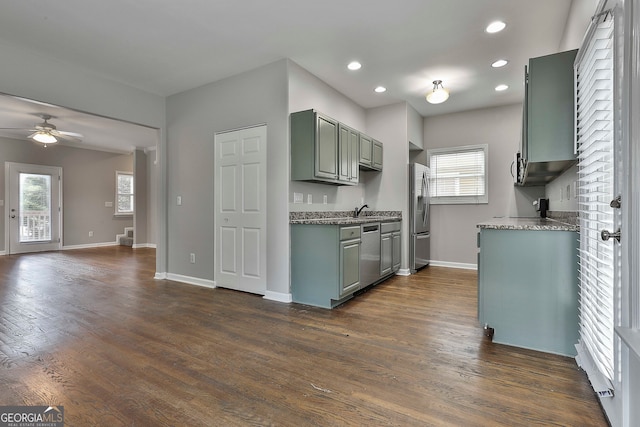 kitchen with stone countertops, dark hardwood / wood-style flooring, sink, ceiling fan, and appliances with stainless steel finishes