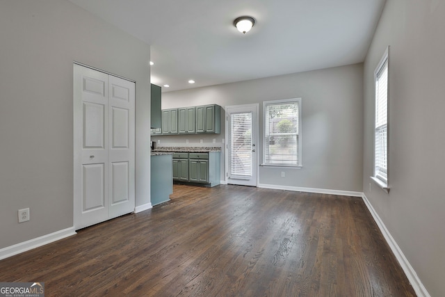 unfurnished living room featuring dark hardwood / wood-style flooring and a healthy amount of sunlight