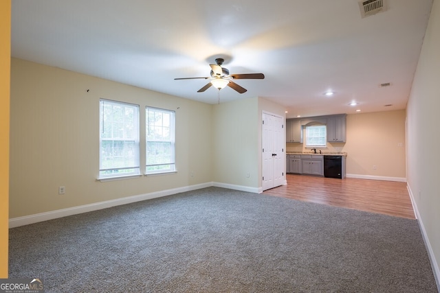 unfurnished living room with hardwood / wood-style floors, ceiling fan, and sink