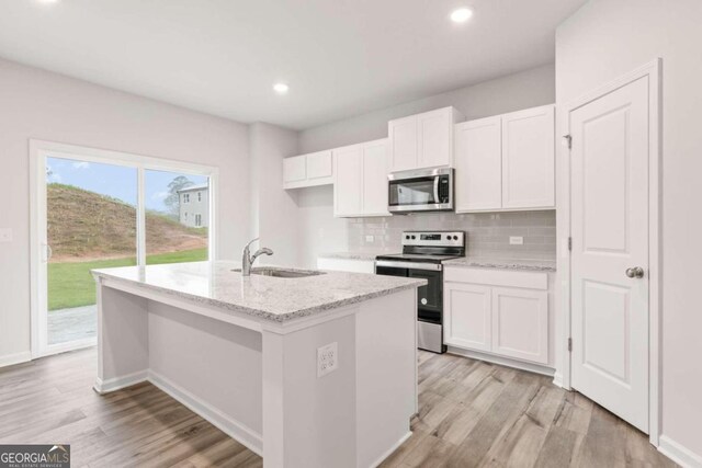 kitchen with white cabinets, appliances with stainless steel finishes, light hardwood / wood-style floors, and sink