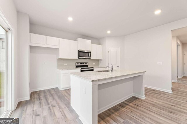 kitchen featuring a center island with sink, appliances with stainless steel finishes, and light hardwood / wood-style flooring