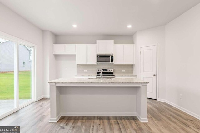 kitchen featuring a center island with sink, light hardwood / wood-style floors, plenty of natural light, and appliances with stainless steel finishes