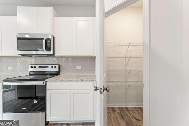 kitchen featuring light stone countertops, stainless steel appliances, tasteful backsplash, dark hardwood / wood-style floors, and white cabinets