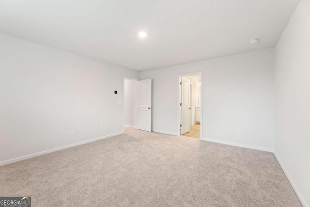 unfurnished bedroom featuring connected bathroom and light colored carpet