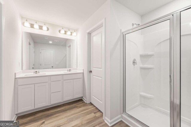 bathroom with hardwood / wood-style floors, vanity, and a shower with shower door