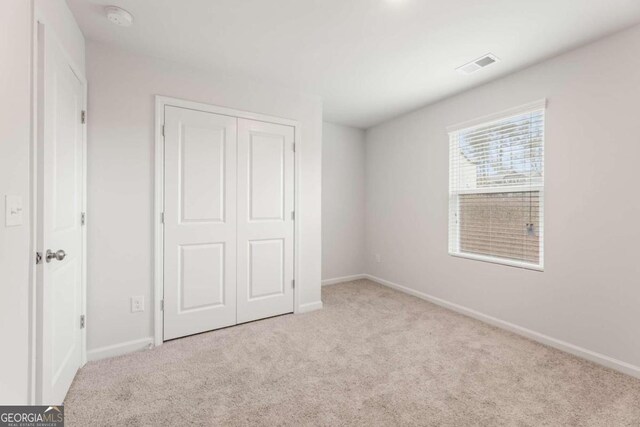 unfurnished bedroom featuring light carpet and a closet