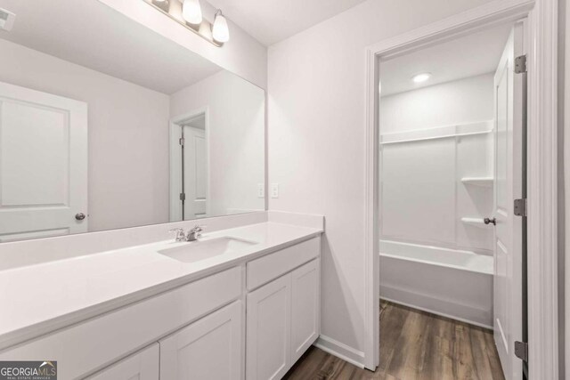 bathroom with bathtub / shower combination, hardwood / wood-style floors, and vanity