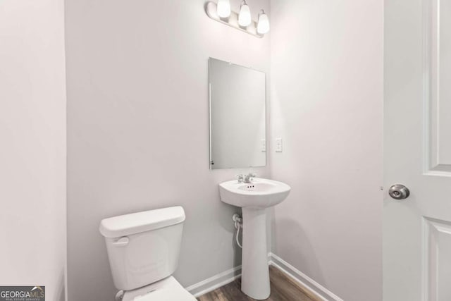 bathroom with hardwood / wood-style flooring, toilet, and sink