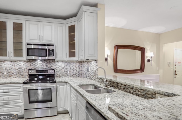 kitchen with light stone countertops, sink, white cabinets, and appliances with stainless steel finishes