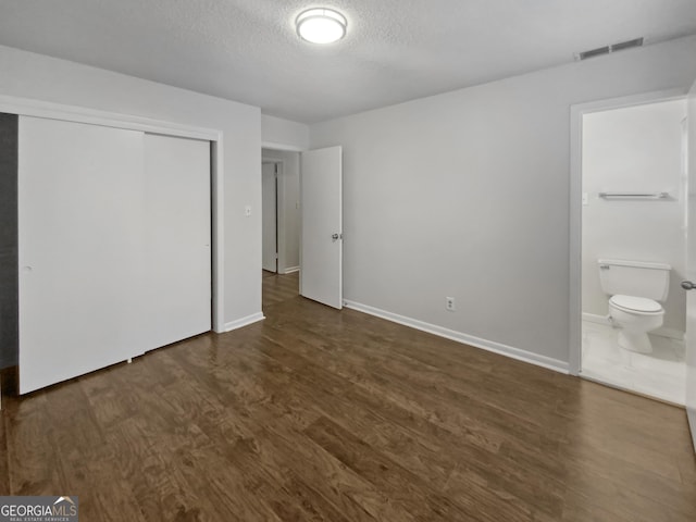 720 Smithstone Rd SE, Marietta, GA 30067 - unfurnished bedroom featuring a closet, a textured ceiling, visible vents, dark wood finished floors, and ensuite bath