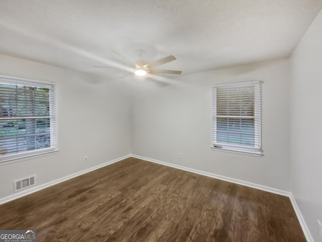 unfurnished room with dark wood-style flooring, visible vents, ceiling fan, and baseboards