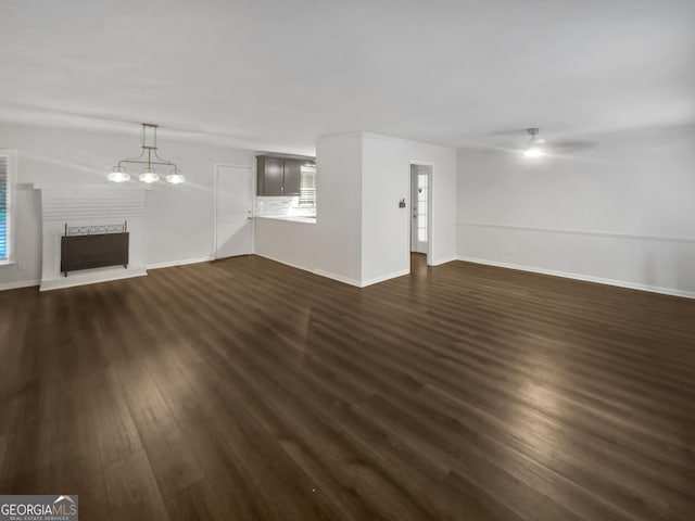 720 Smithstone Rd SE, Marietta, GA 30067 - unfurnished living room featuring ceiling fan with notable chandelier, a fireplace with raised hearth, dark wood-type flooring, and baseboards