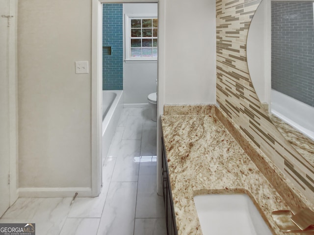 bathroom featuring toilet, marble finish floor, vanity, and baseboards