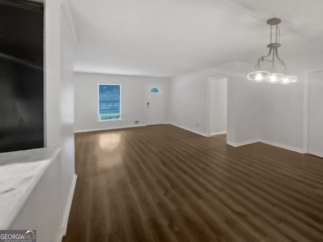 unfurnished living room featuring dark hardwood / wood-style flooring and a notable chandelier