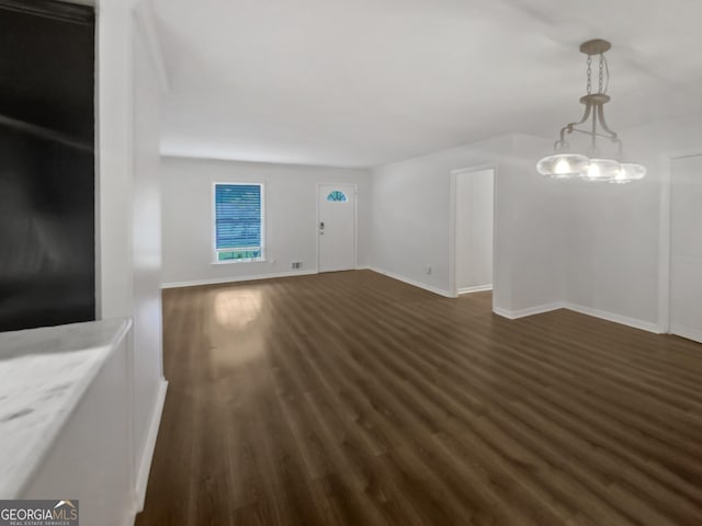 unfurnished living room featuring dark wood-type flooring and baseboards