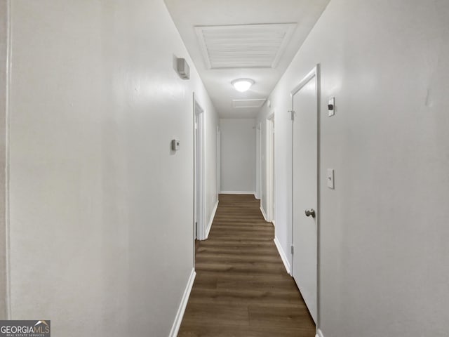 corridor with attic access, visible vents, dark wood finished floors, and baseboards