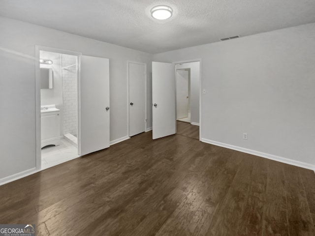 unfurnished bedroom with visible vents, a textured ceiling, baseboards, and wood finished floors