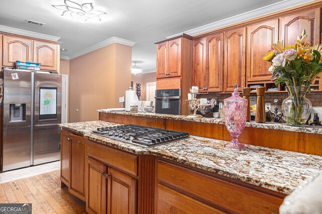 kitchen featuring light wood-type flooring, crown molding, backsplash, stainless steel appliances, and light stone countertops