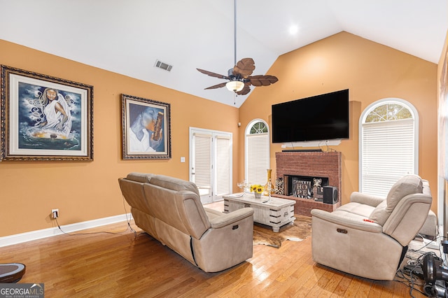 living room featuring lofted ceiling, ceiling fan, light wood-type flooring, and a fireplace