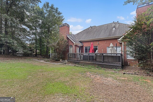 back of property with a lawn and a wooden deck