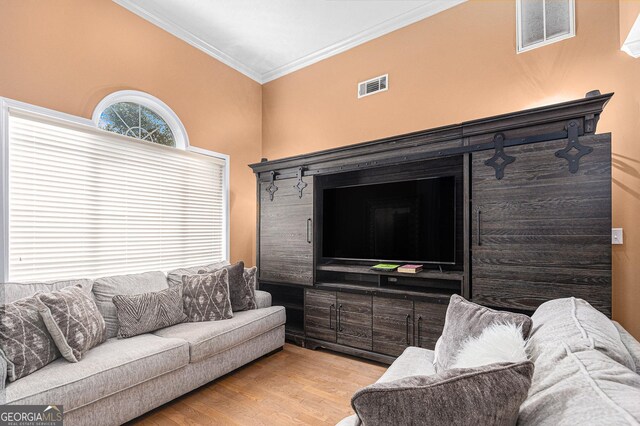 living room featuring ornamental molding, a towering ceiling, and light hardwood / wood-style flooring