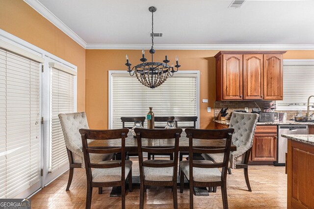 dining room with crown molding, light wood-type flooring, a chandelier, and a healthy amount of sunlight