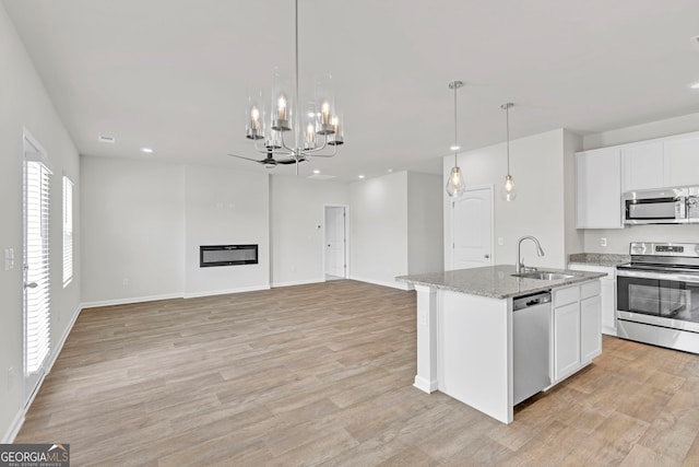 kitchen featuring white cabinetry, stainless steel appliances, sink, and a center island with sink