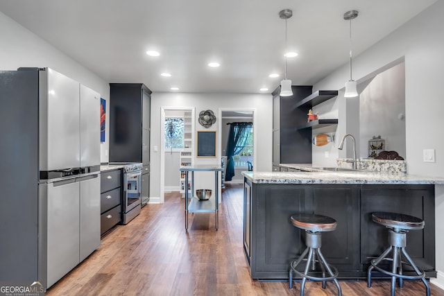 kitchen featuring appliances with stainless steel finishes, hanging light fixtures, a peninsula, and open shelves