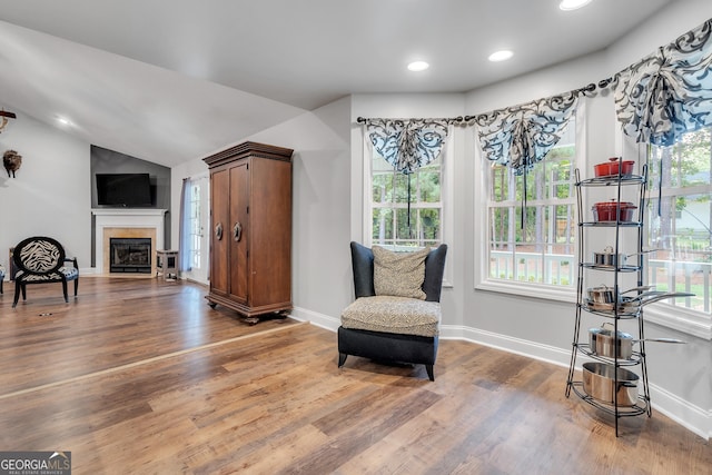 sitting room featuring a tiled fireplace, baseboards, vaulted ceiling, and wood finished floors