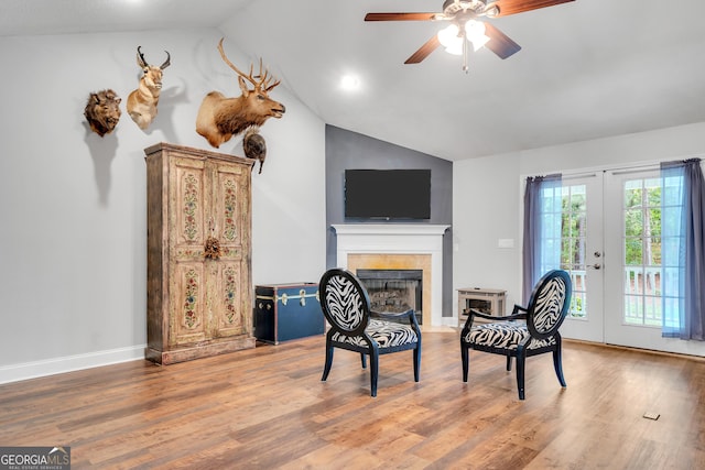 sitting room featuring vaulted ceiling, french doors, a fireplace, and wood finished floors