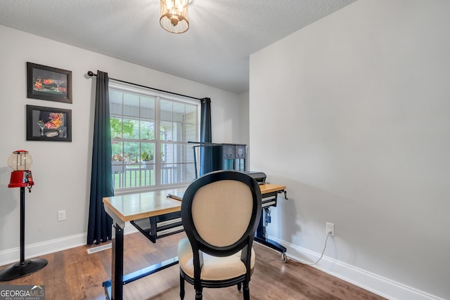 office area with a textured ceiling, baseboards, and wood finished floors