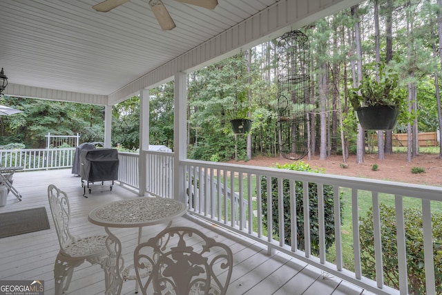 wooden deck with grilling area and a ceiling fan