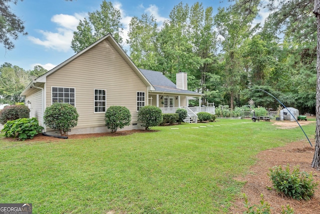 rear view of property with crawl space, covered porch, a lawn, and a chimney