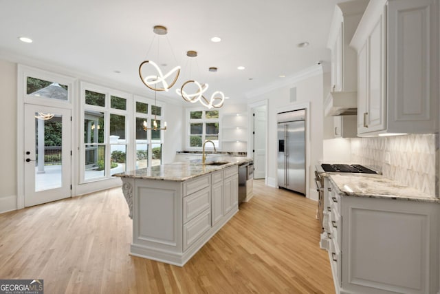 kitchen featuring sink, hanging light fixtures, an island with sink, premium appliances, and white cabinetry