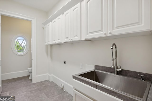 clothes washing area with hookup for an electric dryer, gas dryer hookup, cabinets, and sink