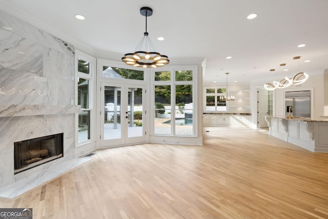 unfurnished living room with a fireplace, french doors, light hardwood / wood-style flooring, and ornamental molding