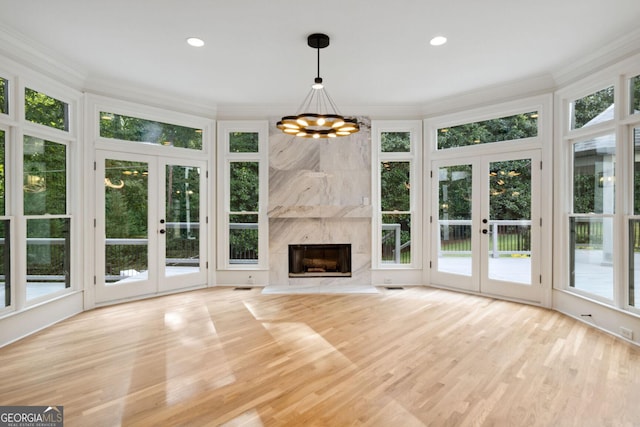 unfurnished sunroom with french doors, a high end fireplace, and a notable chandelier