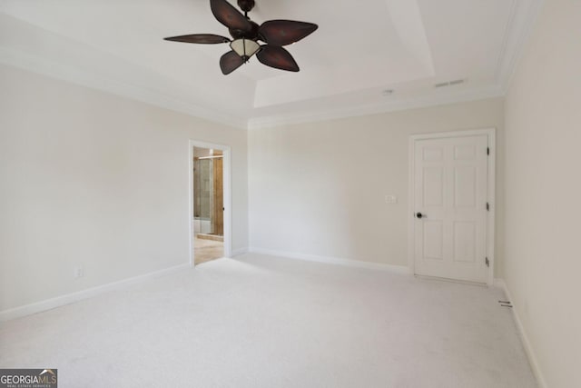 unfurnished room featuring a tray ceiling, crown molding, ceiling fan, and light colored carpet