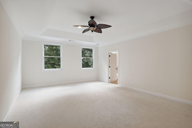 unfurnished room with a raised ceiling, crown molding, ceiling fan, and light colored carpet