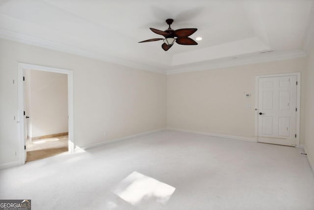 spare room with a tray ceiling, light carpet, crown molding, and ceiling fan