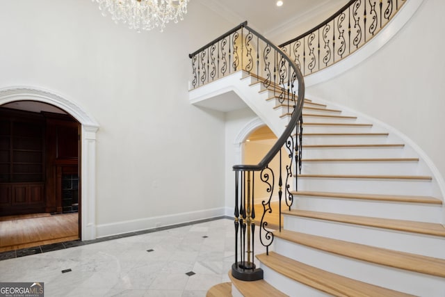 foyer with crown molding, a towering ceiling, a chandelier, and wood-type flooring