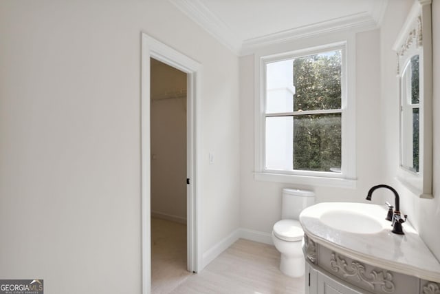 bathroom with crown molding, vanity, wood-type flooring, and toilet